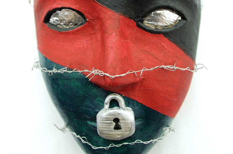 A red and black mask featuring a lock over the mouth and razor wire. One of the masks created through the art therapy program at Walter Reed National Military Medical Center that has partnered with Drexel College of Nursing and Health Professions.